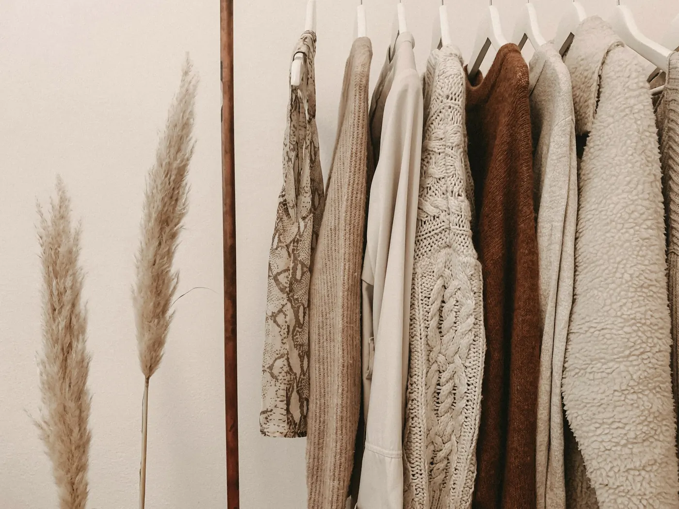 Arara com roupas em tons neutros ao lado de um vaso com capim-dos-pampas